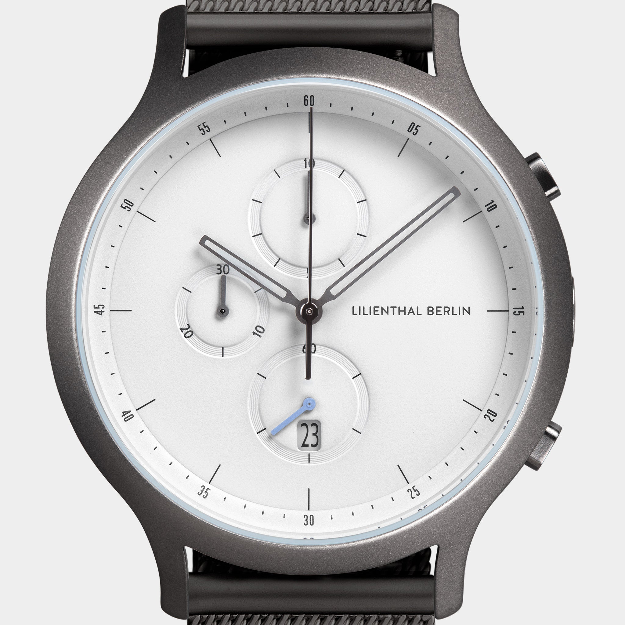Minimalist chronograph watch with white dial, three subdials, date display, and mesh strap.