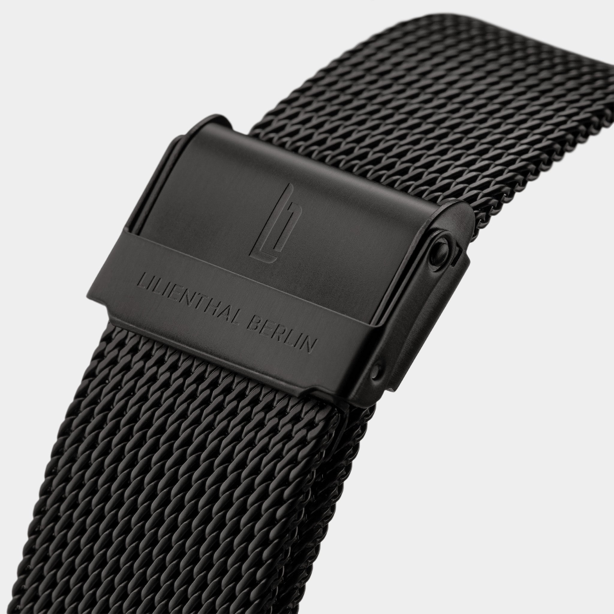 Black mesh stainless steel watch strap with engraved clasp closeup