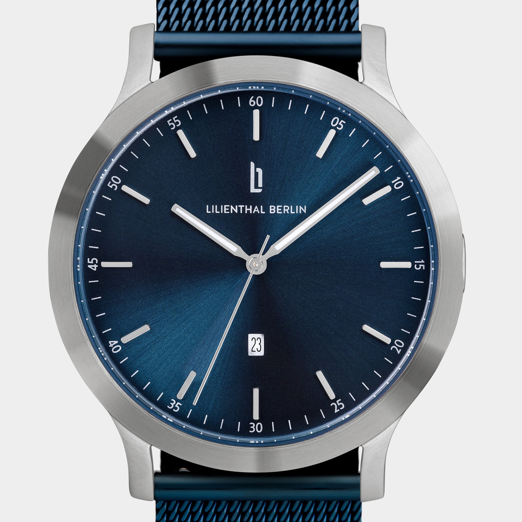 Minimalist blue dial watch with silver case, mesh strap, and date display