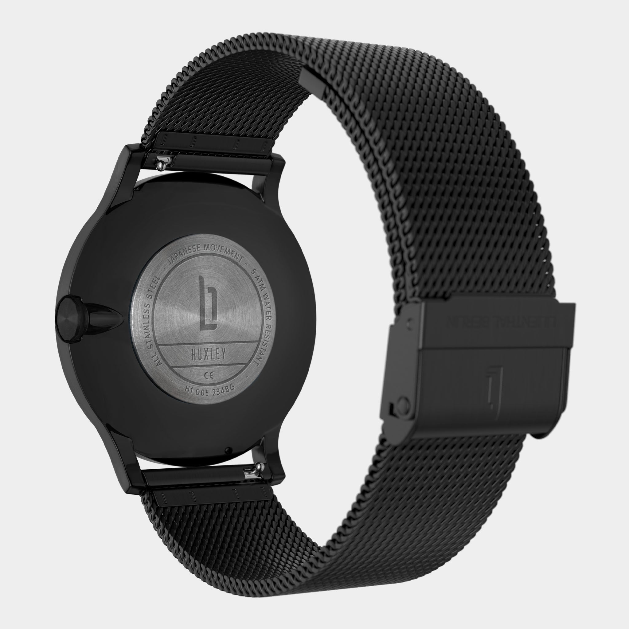 Close-up of a black stainless steel mesh watch strap and engraved watch back