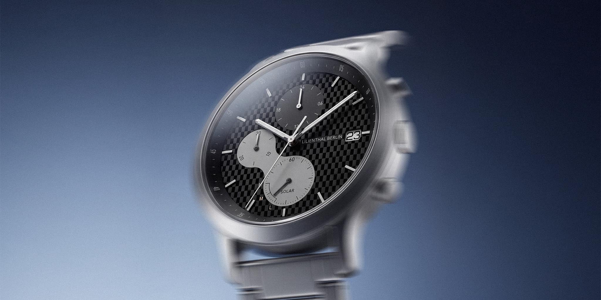 Silver chronograph wristwatch with textured black dial, subdials, and date display on blue gradient background