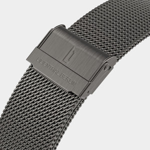 Close-up of a stainless steel mesh watch strap with clasp and engraved branding