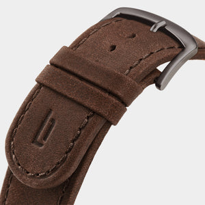 Close-up of brown leather watch strap with metal buckle and stitched detailing