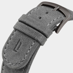 Close-up of a grey suede watch strap with stitching and metal buckle