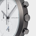 Close-up of a modern chronograph watch with white dial and metal pushers