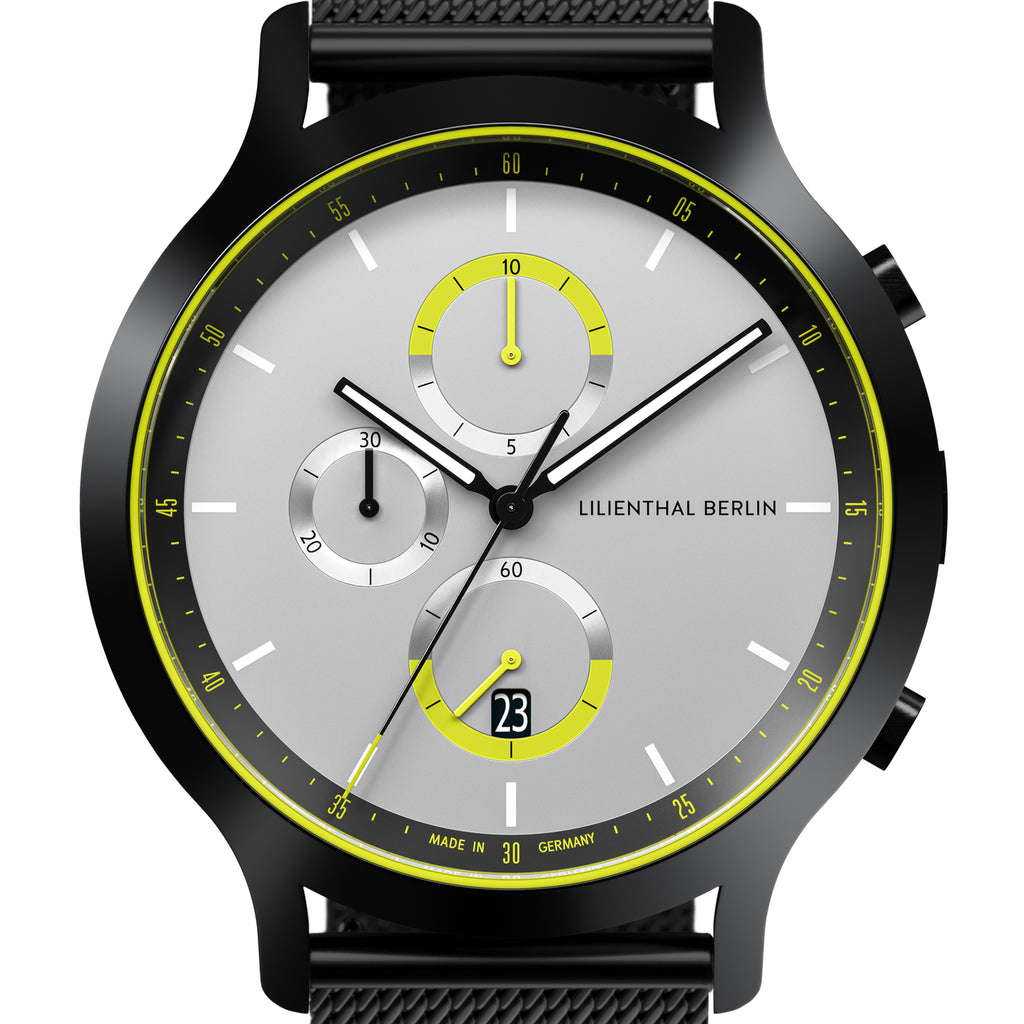 Modern chronograph watch with black case, silver dial, yellow accents, subdials, and date display
