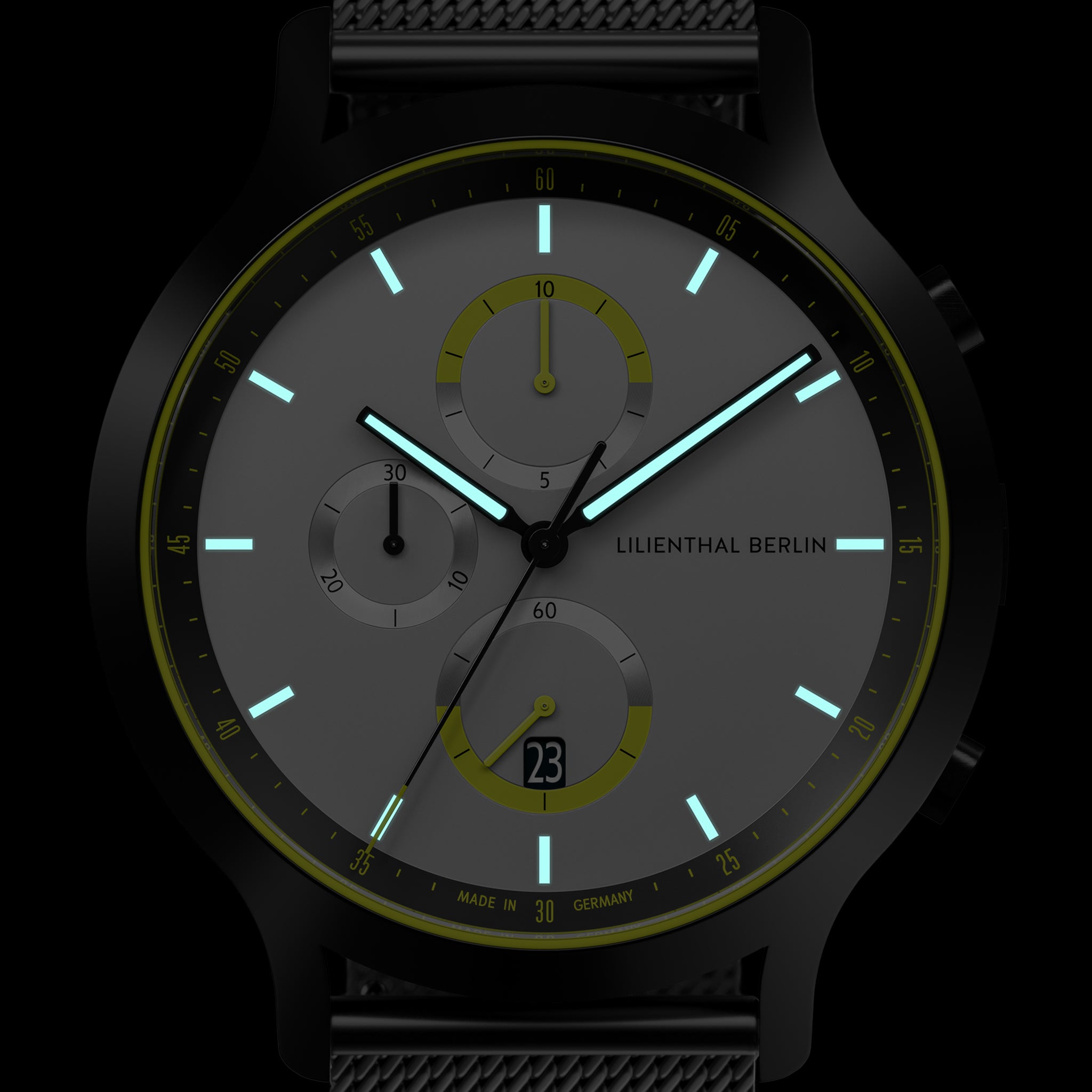 Modern chronograph watch with glowing hands, black case, and mesh band on dark background