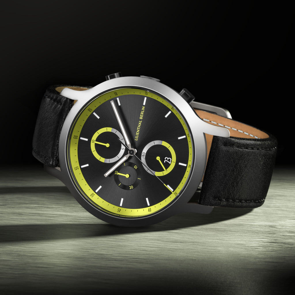 Modern black chronograph watch with neon yellow accents and black leather strap, close-up