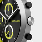 Close-up of modern chronograph watch with black dial, yellow accents, and silver case.