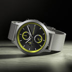 Modern chronograph watch with black and yellow dial, silver mesh strap, and bold accents