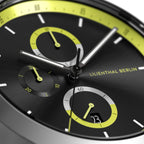 Close-up of modern black watch face with yellow accents, subdials, and date display