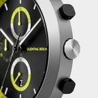 Close-up of modern chronograph watch with black and yellow dial, silver case, side buttons