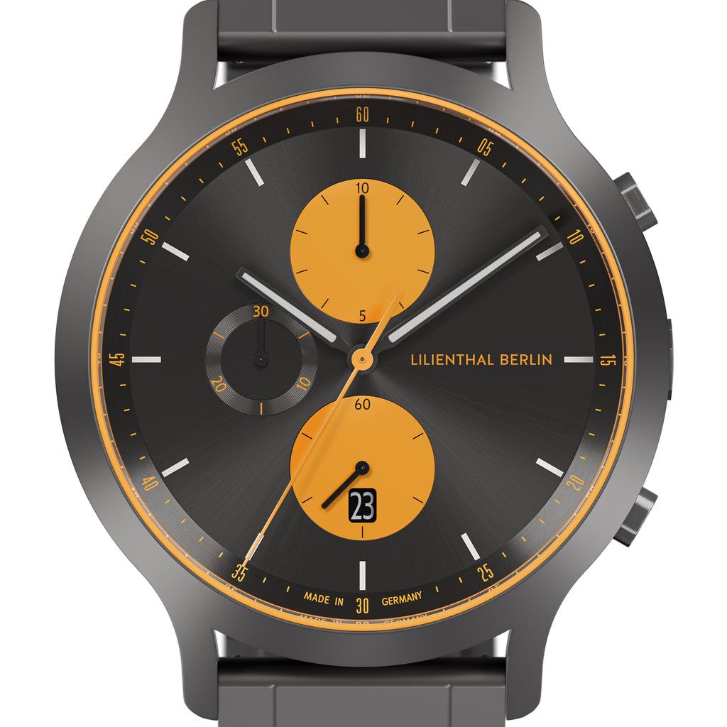 Modern chronograph watch with black dial, orange subdials, date display, and grey strap