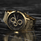 Luxury gold chronograph watch with black dial on a polished marble surface