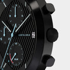 Close-up of a modern black chronograph watch with textured dial and solar subdial display.