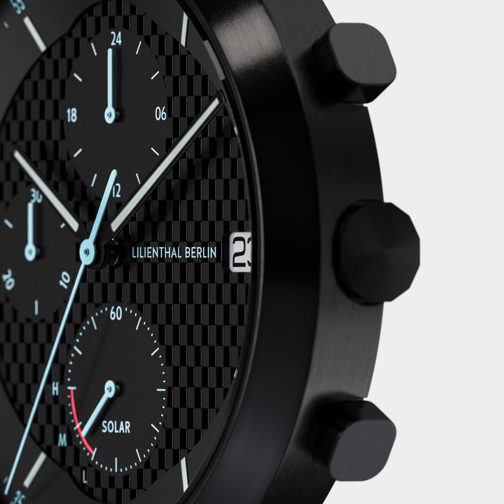 Close-up of a black chronograph watch with textured dial, subdials, and solar indicator