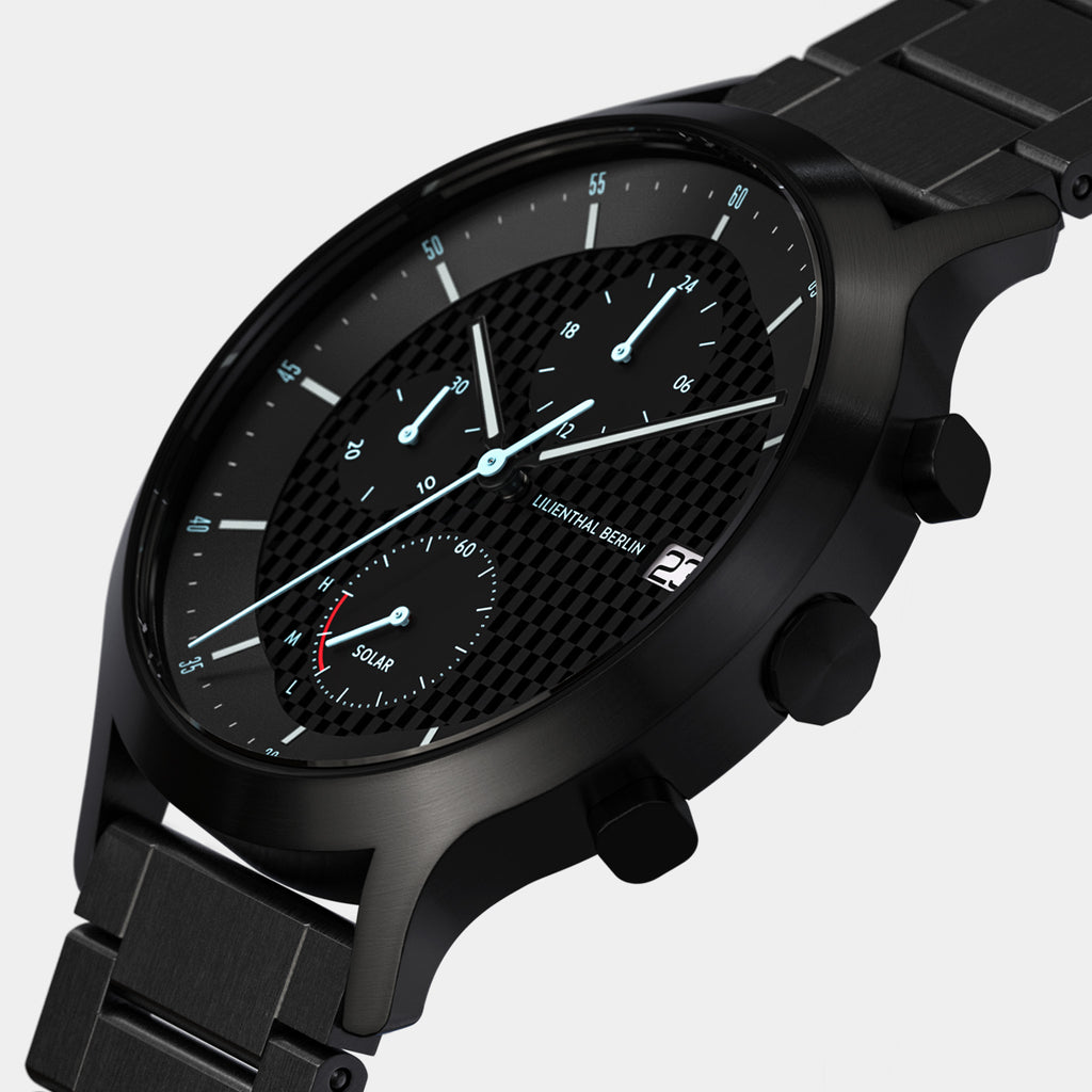 Close-up of a black solar-powered chronograph watch with steel bracelet and textured dial.