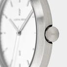 Close-up of minimalist silver watch with brushed metal case and white dial
