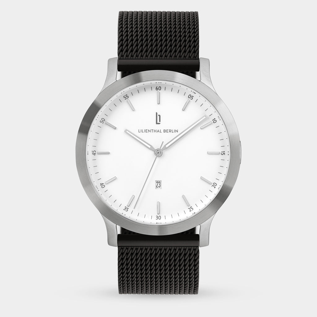 Minimalist silver wristwatch with white dial, black mesh strap, and date display