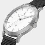 Minimalist silver wristwatch with white dial and black mesh strap, close-up view