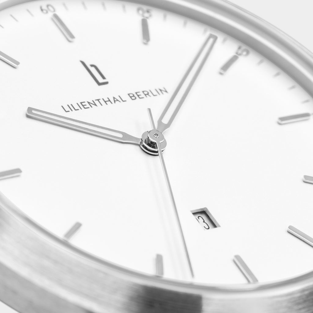 Minimalist silver and white wristwatch close-up with date display and sleek hands