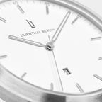 Minimalist silver and white wristwatch close-up with date display and sleek hands