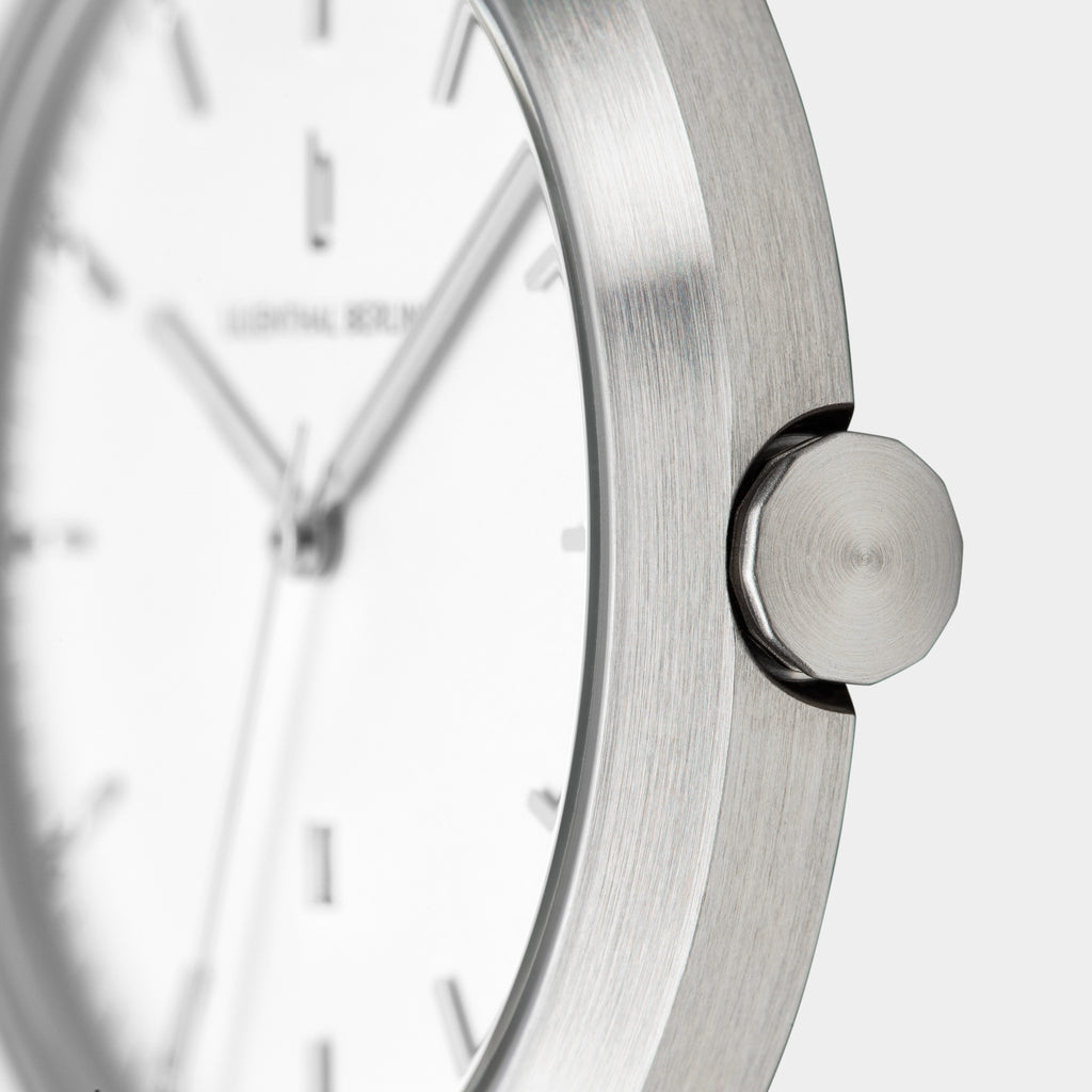 Minimalist silver watch close-up with brushed metal case and white dial