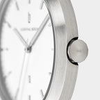 Minimalist silver watch close-up with brushed metal case and white dial