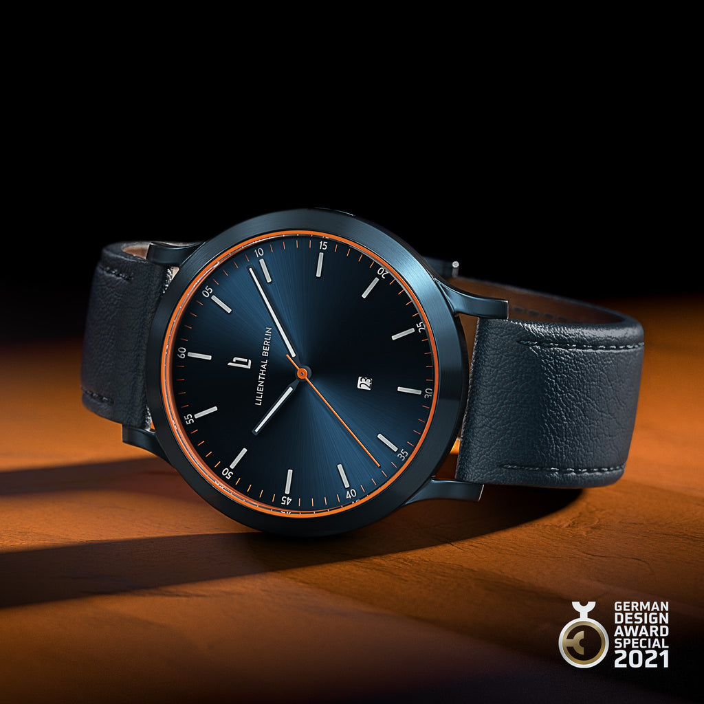Modern black watch with blue dial, orange accents, date display, leather strap, award badge
