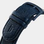 Close-up of dark blue textured leather watch strap with black buckle