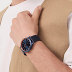 Elegant blue minimalist watch with mesh strap on wrist, paired with beige vest and white shirt