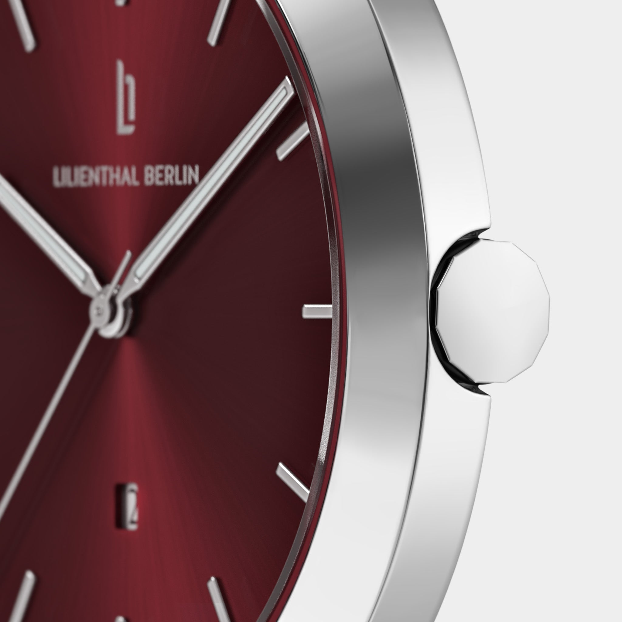 Close-up of silver minimalist watch with red dial and date display