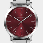 Close-up of a stainless steel watch with a red sunburst dial and date display