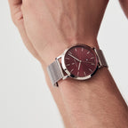 Silver mesh strap watch with burgundy dial and minimalist design on wrist