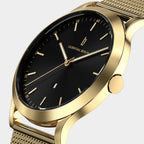 Gold minimalist watch with black dial, mesh strap, and date display on white background