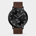 Minimalist black dial wristwatch with brown leather strap and subdial, modern design