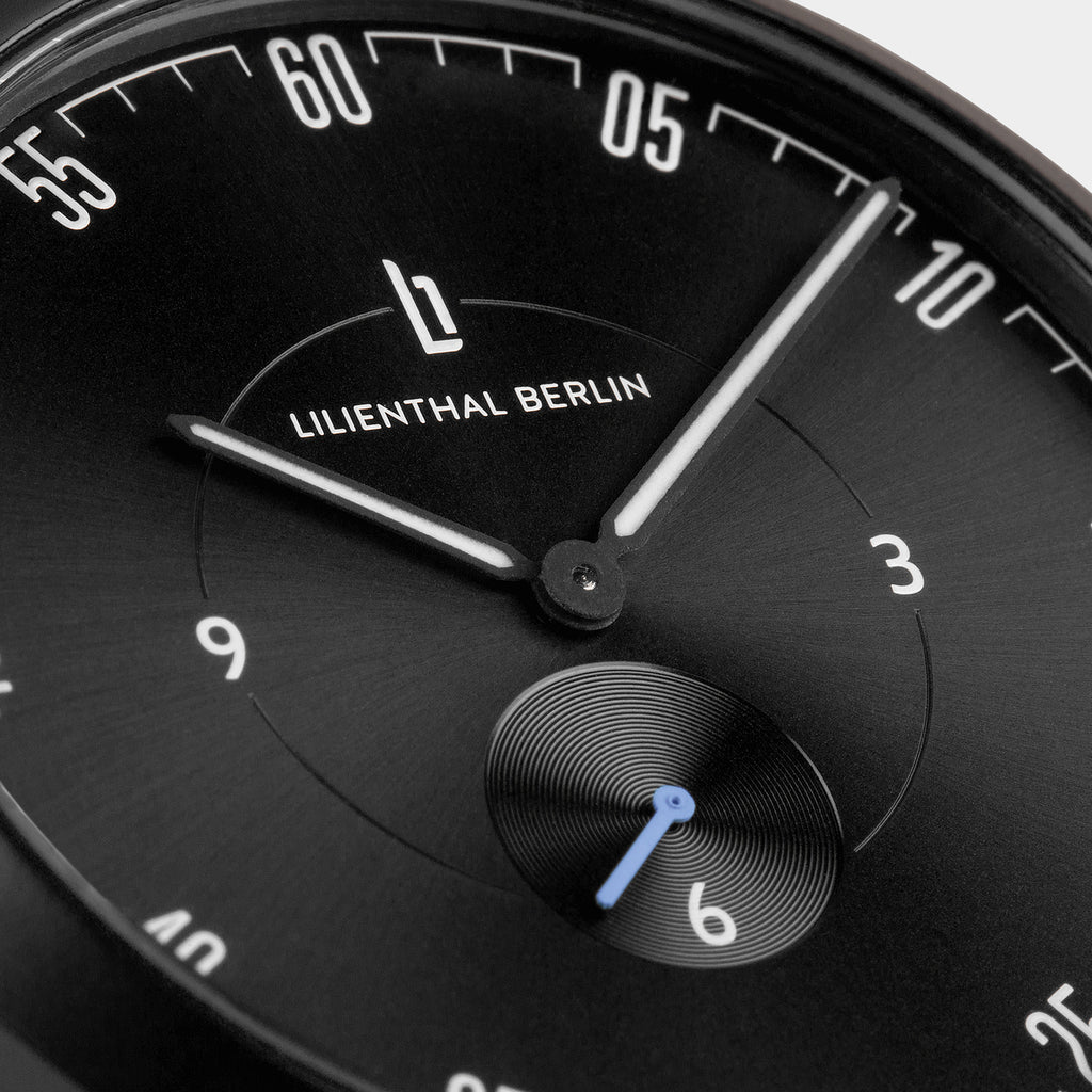 Black minimalist wristwatch close-up with white hands and Lilienthal Berlin logo on dial