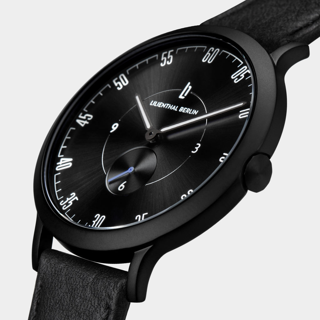 Minimalist black analog wristwatch with sunburst dial and black leather strap