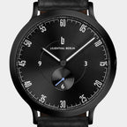 Black minimalist watch with white markers, subdial, and black leather strap on white background