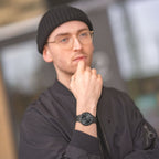 Man wearing minimalist black wristwatch and black beanie, dressed in black jacket