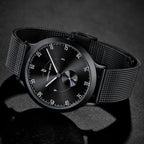 Minimalist black mesh strap wristwatch with black dial on a dark background