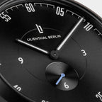 Close-up of a black minimalist watch face with white hands and Lilienthal Berlin logo
