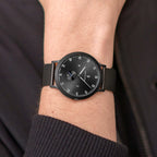 Minimalist black analog watch with mesh band on wrist, modern and stylish design