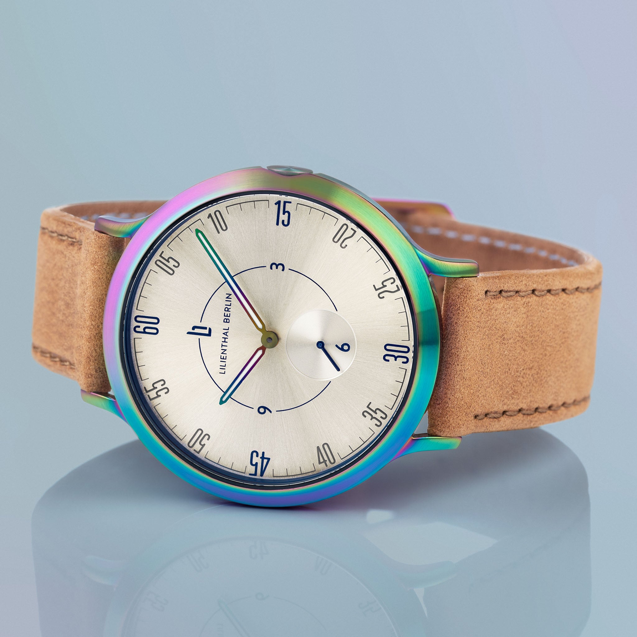 Minimalist watch with iridescent case, tan leather strap, and silver dial on blue background